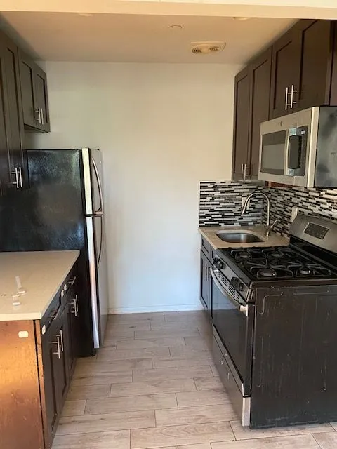 Caesar Pl 2L kitchen with dark cabinets, stainless steel appliances, and a mosaic backsplash
