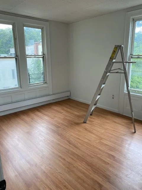 Hillside Ave #3S room with hardwood floors, multiple windows, and a baseboard heater