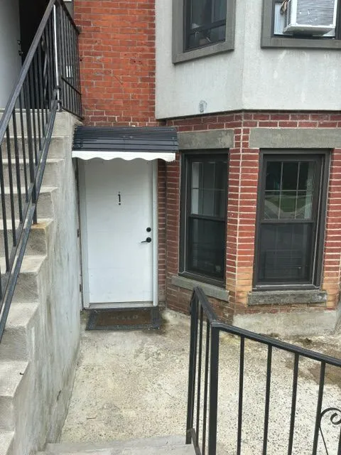 Yonkers Ave #1 exterior entry with stairs, a white door, and brick walls