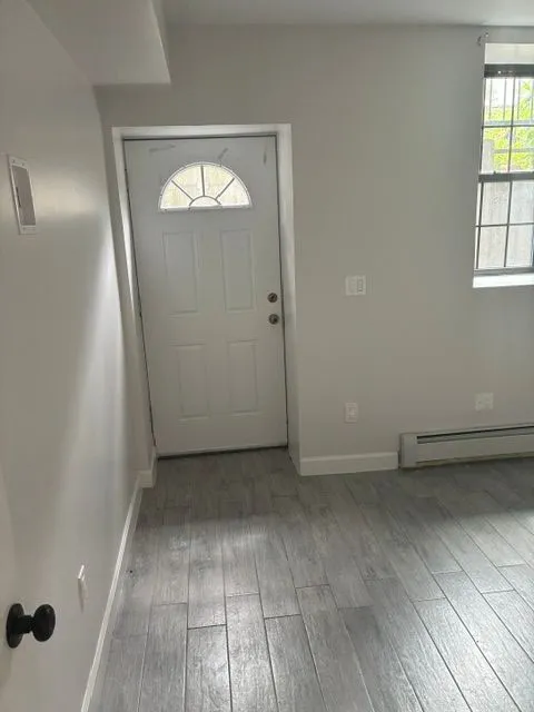 Yonkers Ave #1 room with a white entry door, window, and gray flooring