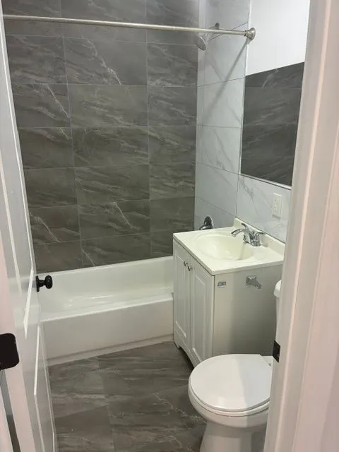 Yonkers Ave #1 bathroom with a white vanity, bathtub, toilet, and gray wall tile