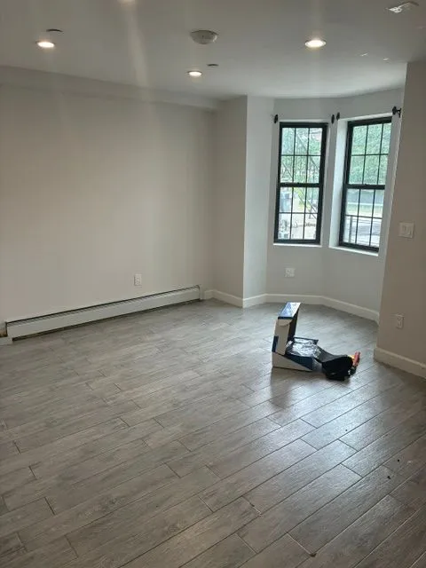 Bright empty Yonkers Ave #1 room with bay windows and gray flooring