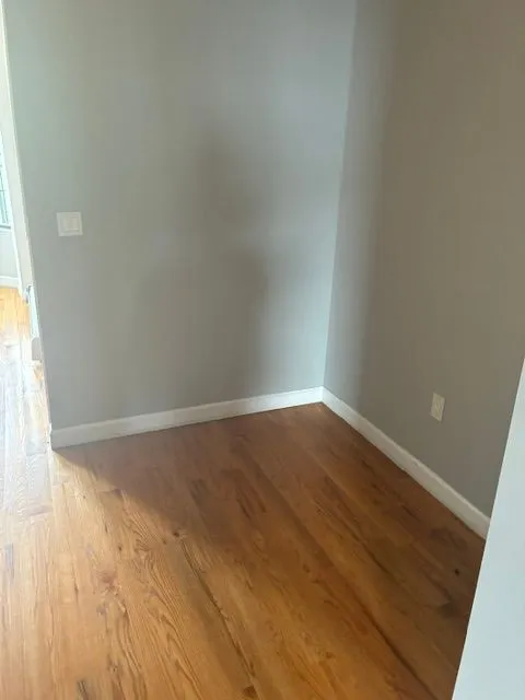 Empty room with hardwood floors and light gray walls