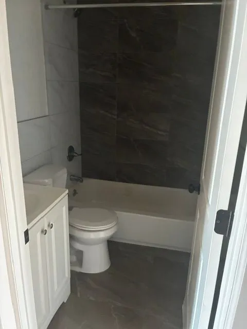 Bathroom with a white vanity, toilet, and tiled tub surround