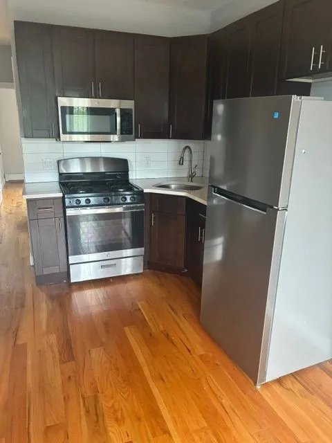 Kitchen with dark cabinets, stainless steel appliances, and hardwood floors
