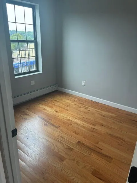 Bright empty room with hardwood floors and a street-facing window