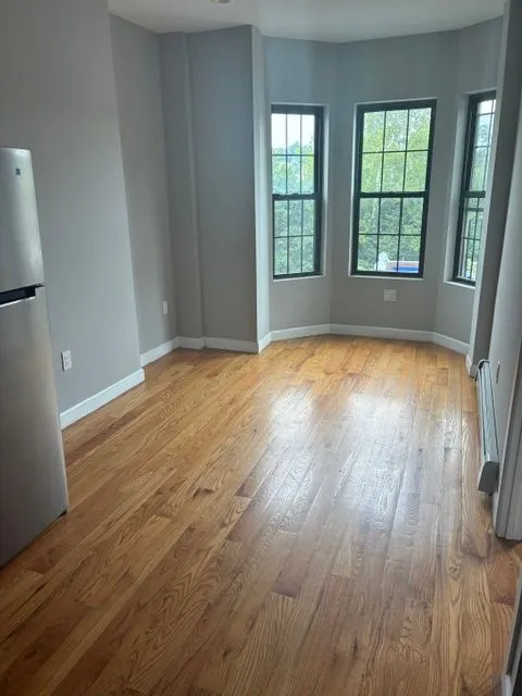 Bright living area with hardwood floors and a three-window bay