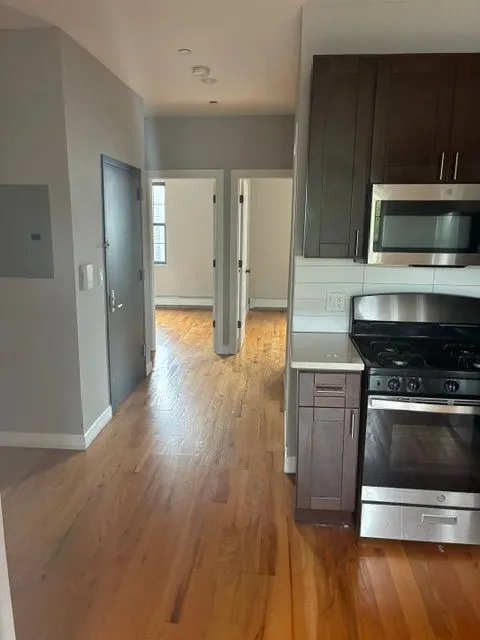 Kitchen and hallway view with dark cabinets and stainless steel range